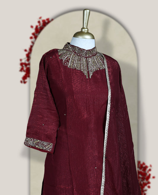 Deep Maroon colour churidar set with a rich sheen, beautifully adorned with golden cut beads work on the neckline and sleeve borders, Paired with a matching dupatta featuring a subtle zari edge, perfect for a regal festive look.