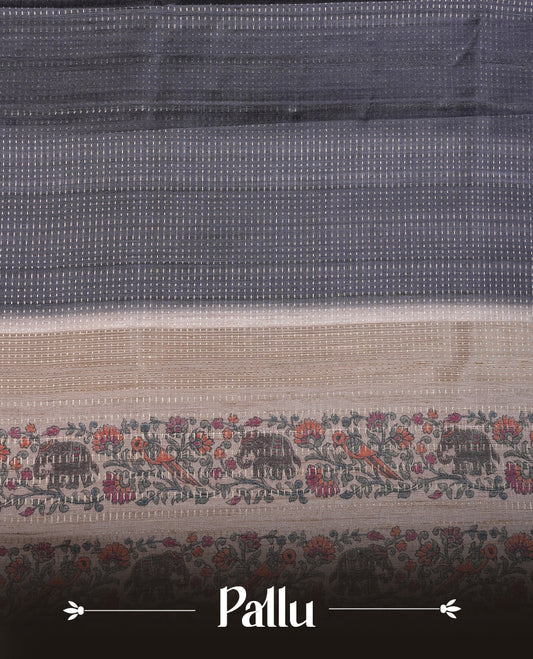 Charcoal black colour tussar saree featuring golden zari dot stripped pattern on the body, complemented by a contrast cream colour mutlicolour floral kodi & animal print on border & pallu, paired with a matching blouse.