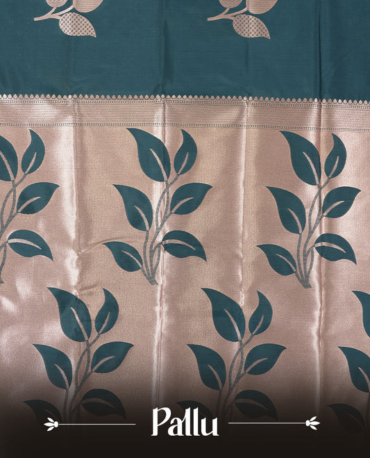 Dark teal blue colour semi silk saree adorned with elegant floral motifs on the body, complemented by a shimmering golden zari-woven pallu and border, and paired with a matching blouse