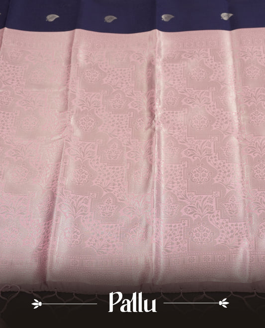 Navy blue colour semi silk saree adorned with subtle silver zari motifs on the body, complemented by contrasted a pastel light pink pallu intricately  woven with rich floral patterns border and pallu, and paired with a matching blouse