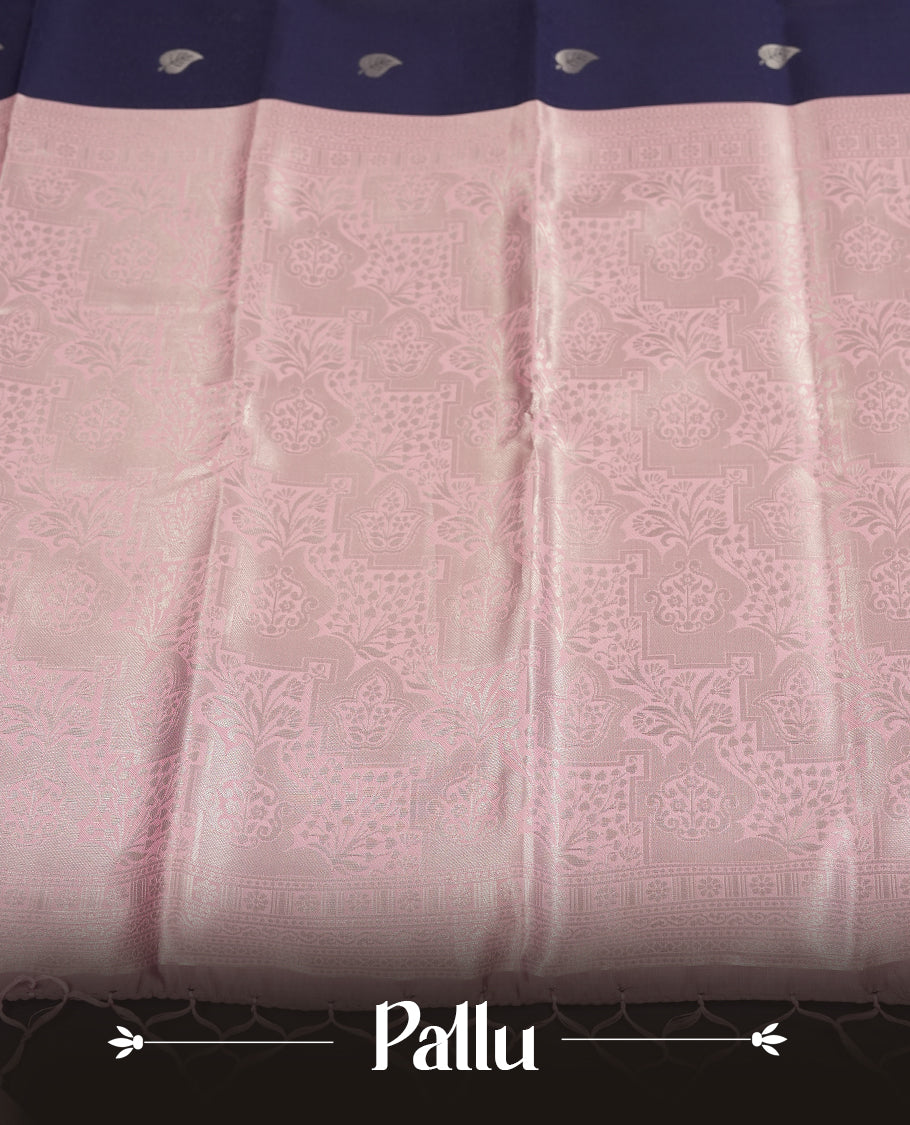 Navy blue colour semi silk saree adorned with subtle silver zari motifs on the body, complemented by contrasted a pastel light pink pallu intricately  woven with rich floral patterns border and pallu, and paired with a matching blouse
