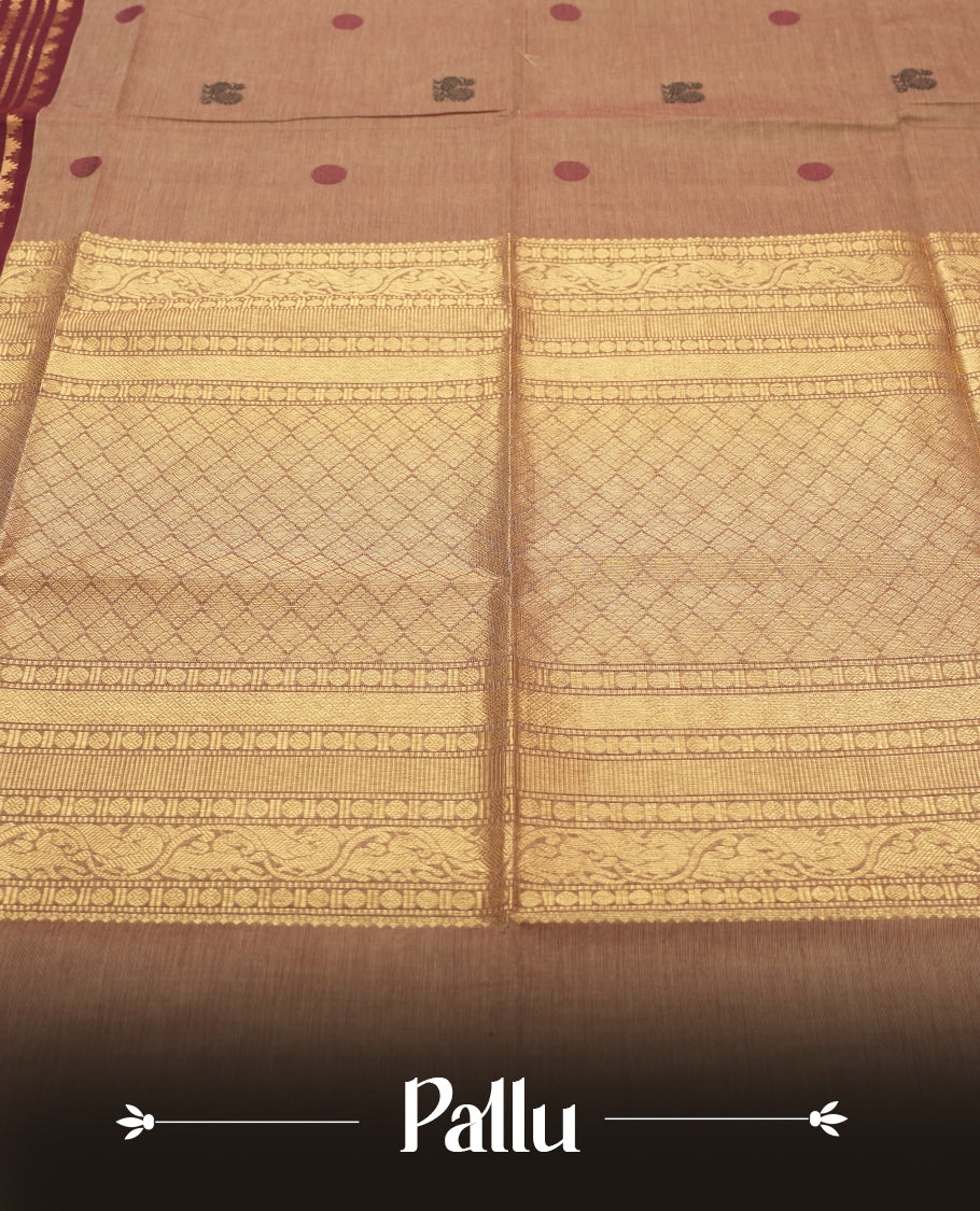 Beige Colour silk cotton saree with scattered maroon and black buttas, ornate maroon and gold zari border with geometric patterns, gold zari pallu with diamond lattice, plain beige blouse with maroon border.