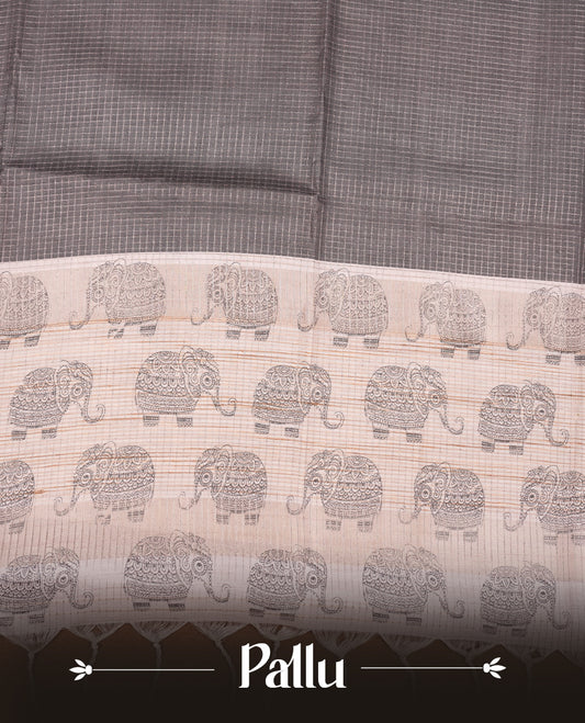 Charcoal green colour semi tussar silk saree featuring an all-over elephant motif print across the body, complemented by a contrasting blue pallu and border, and paired with a matching blouse piece.