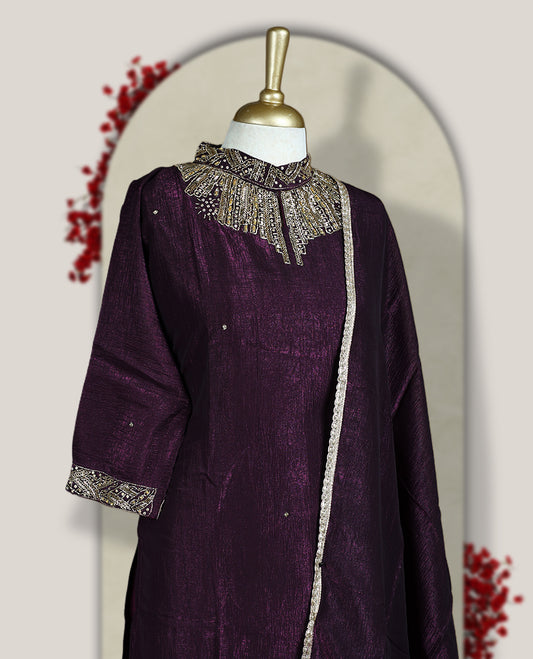 Deep wine colour churidar set with a rich sheen, beautifully adorned with golden cut beads work on the neckline and sleeve borders, Paired with a matching dupatta featuring a subtle zari edge, perfect for a regal festive look.