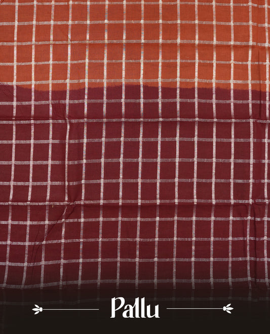 Brown colour Chettinad cotton saree featuring a silver zari checkered body, paired with a contrast maroon pallu highlighted by a silver zari floral border, and a matching maroon checkered blouse piece with silver zari detailing.