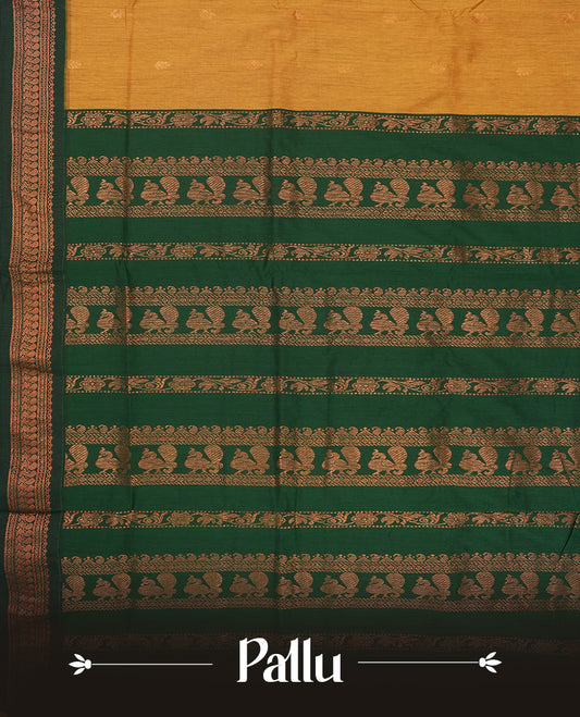 Mustard yellow colour Kalyani Cotton saree with golden motifs, paired with a contrasting green border featuring intricate peacock zari work & Comes with a matching blouse piece.