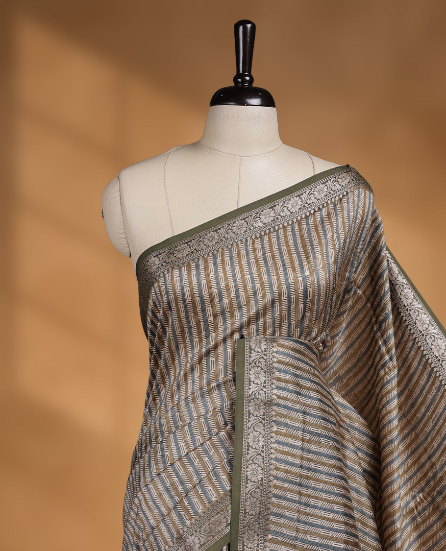 Cream colour chanderi silk saree with Olive & blue geometric stripped printed On body, compilmented by contrast olive colour border with golden zari floral pattern and a matching blouse.