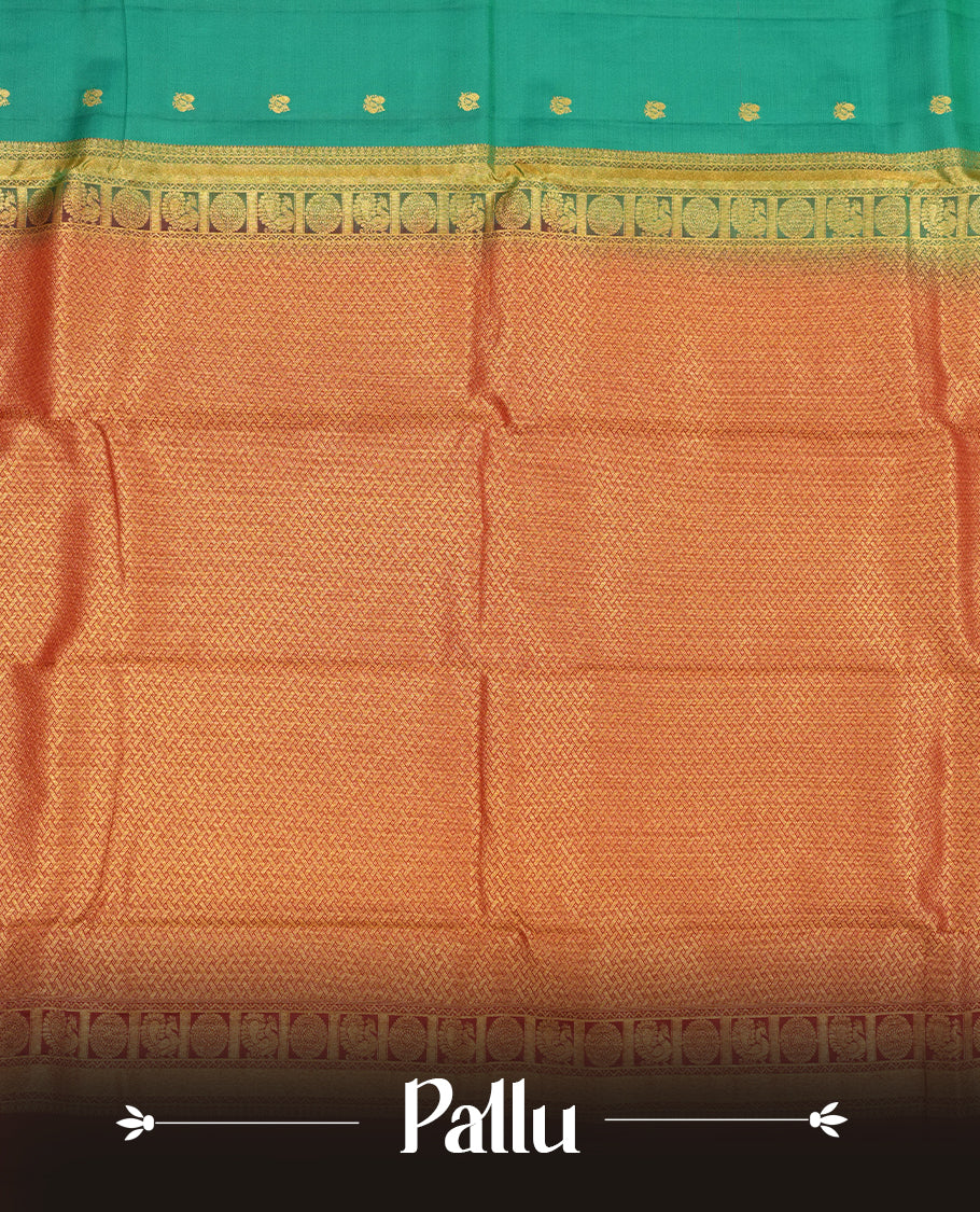 Green colour Vasundhara silk saree adorned with all-over gold mayil motifs on the body, complemented by a  contrast maroon colour with gold traditional border and paired with a matching blouse piece.