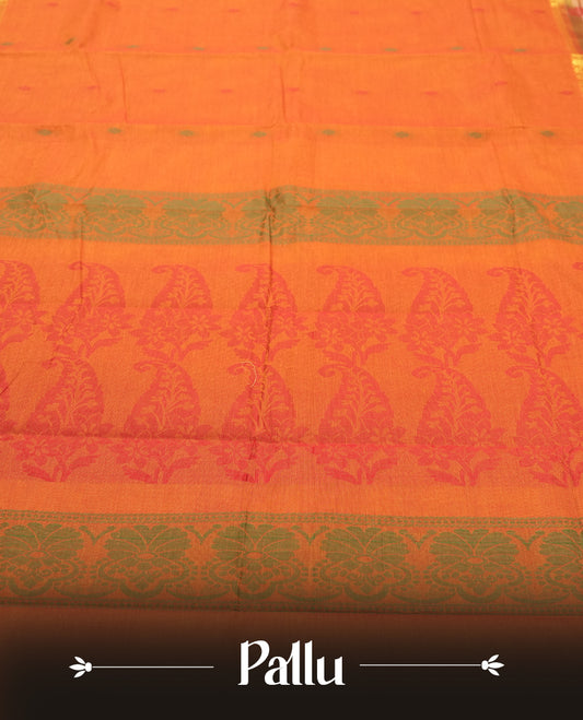 Burnt Orange colour Silk Cotton Saree with Contrast Green Zari Border featuring Ikat-inspired floral panels, Small Dual-Tone Buttas on the Body, Paisley-Woven Pallu, and a Coordinated Matching Blouse Piece