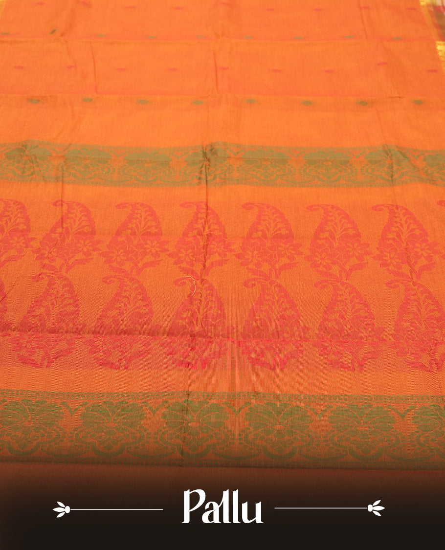 Burnt Orange colour Silk Cotton Saree with Contrast Green Zari Border featuring Ikat-inspired floral panels, Small Dual-Tone Buttas on the Body, Paisley-Woven Pallu, and a Coordinated Matching Blouse Piece