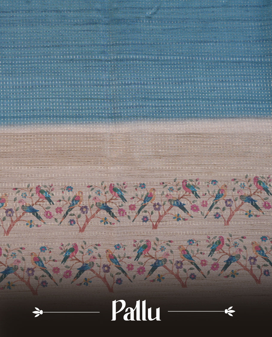 Teal colour tussar saree featuring golden zari dot stripped pattern on the body, complemented by a contrast cream colour mutlicolour floral kodi & animal print on border & pallu, paired with a matching blouse.