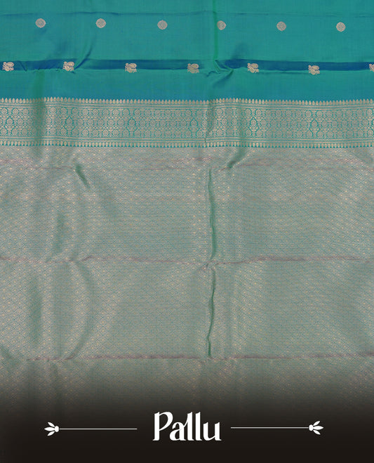 Peacock green colour Vasundhara silk saree adorned with all-over gold chakkaram& mayil motifs on the body, complemented by a self colour with rose gold traditional border and paired with a matching blouse piece.