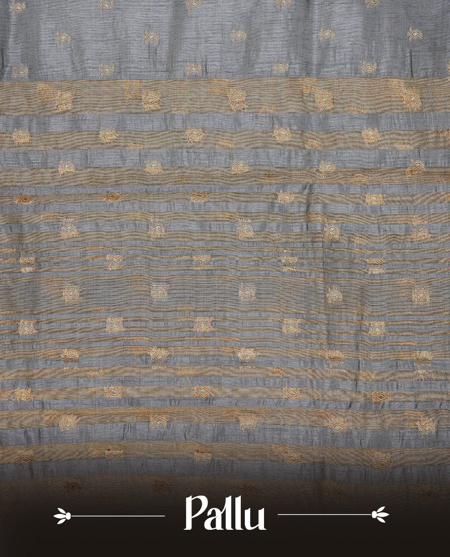 Grey colour semi tussar silk saree featuring small gold zari mango motifs across the body, enhanced with a self colour border showcasing elegant gold zari mango patterns. Paired with a matching blouse piece.