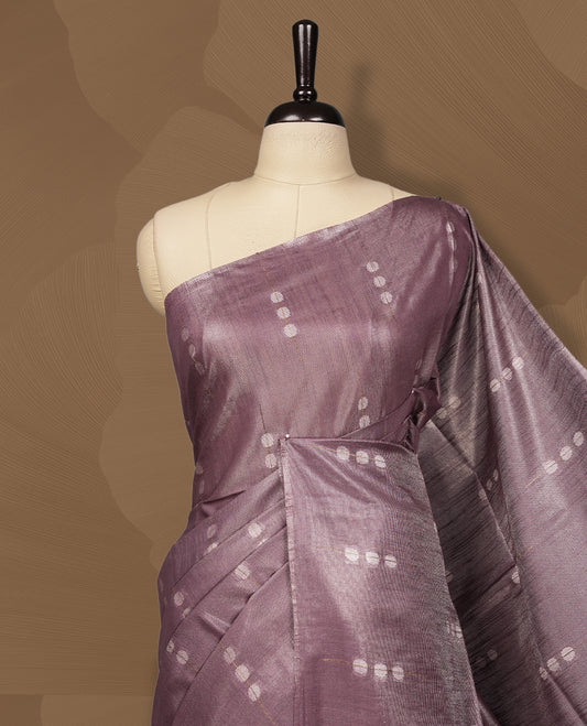Mauve semi jute tissue saree featuring subtle dotted woven patterns on the body, complemented by a shimmering pallu and sleek zari border & Comes with a matching blouse piece for a complete look.