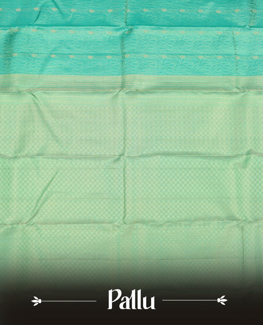 Aqua Green colour Vasundhara silk saree adorned with all-over green flower kodi motifs on the body, complemented by a  self colour with gold Line pattern border and paired with a matching blouse piece.