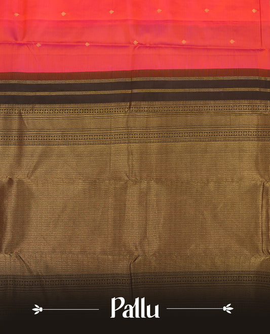 Pinkish red colour Vasundhara silk saree adorned with all-over gold zari motifs on the body, complemented by a contast black colour with gold motifs on border and paired with a matching blouse piece.