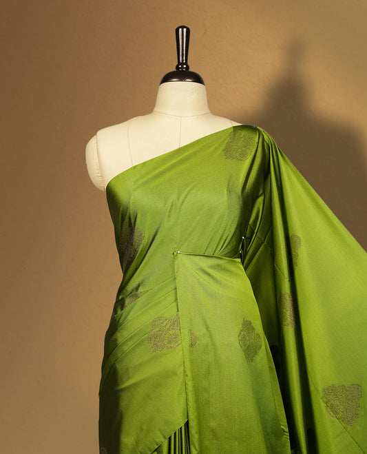 Olive green colour semi soft silk saree adorned with delicate woven self motifs on the body, complemented by a rich contrast navy blue colour woven pallu with intricate detailing and tassel accents & Comes with a matching blouse piece.