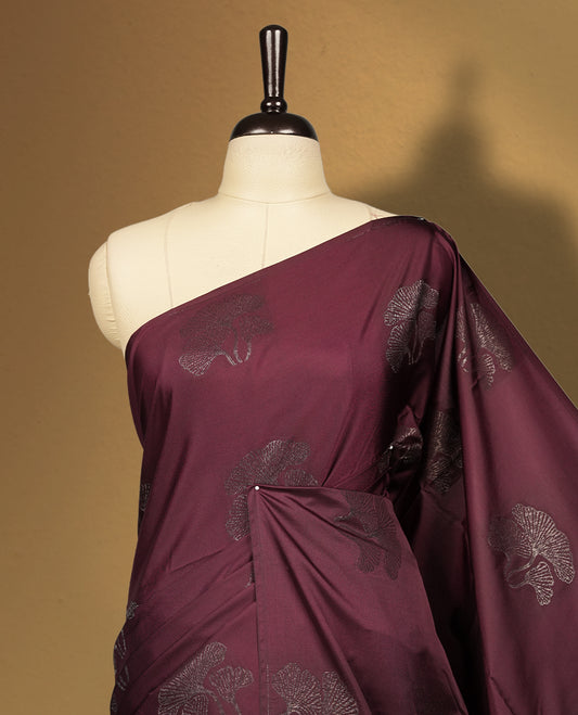 Deep brown colour semi soft silk saree, adorned with subtle floral woven motifs on the body & The design is elevated with an elegant zari border and pallu, paired with a matching blouse.