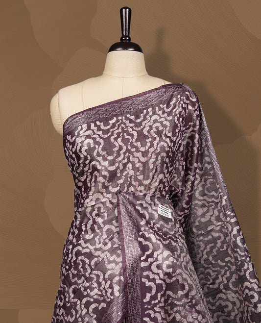 Chocolate colour semi jute tissue saree featuring intricate wave motifs all over the body, enhanced with a shimmering zari striped pallu, woven border, and matching blouse piece.