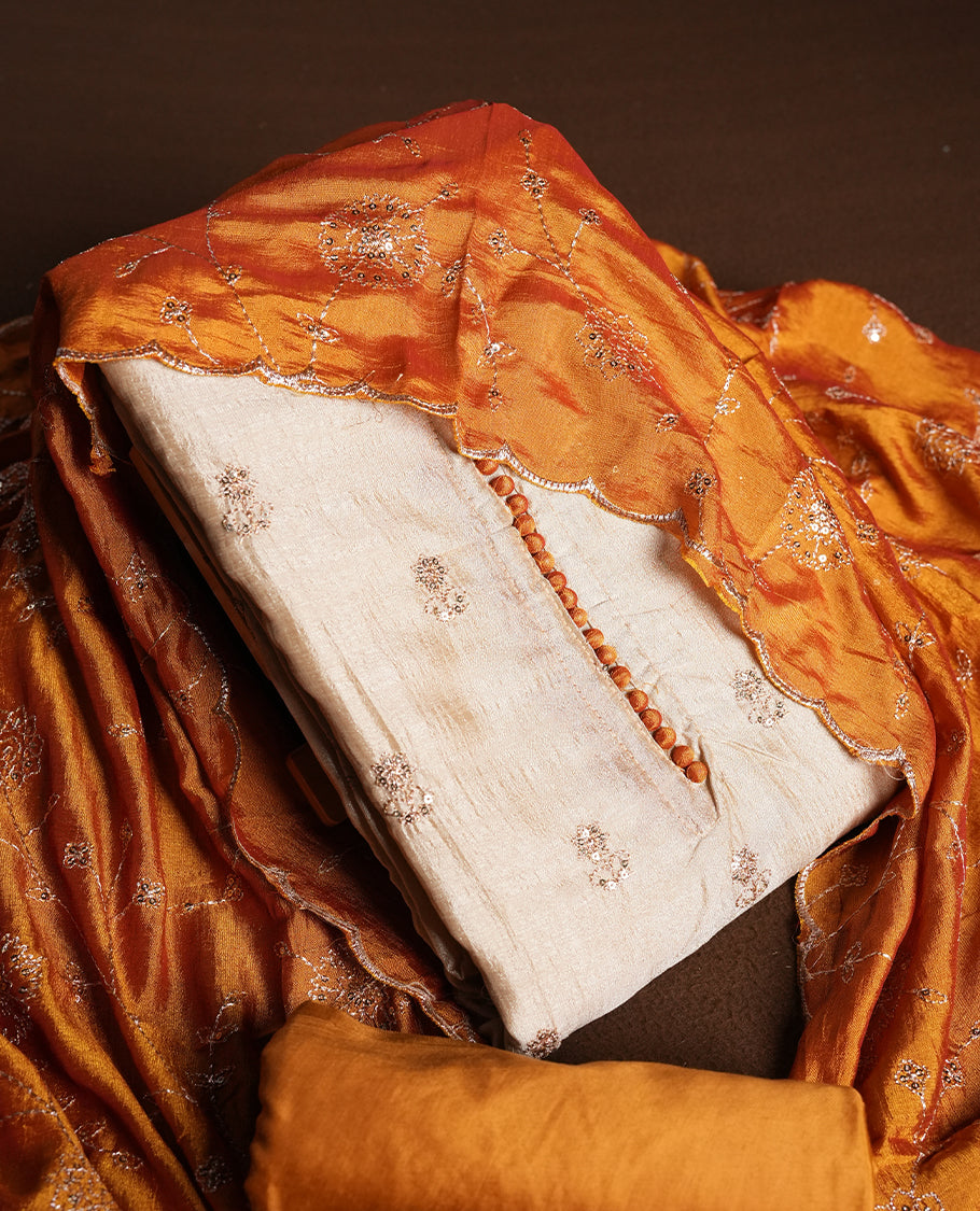 Golden Cream colour churidhar material featuring thread embroidery on the front panel, contrast orange colour dupatta with elegant border, and matching plain bottom