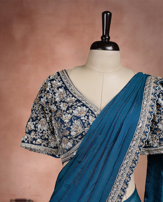Elegant Teal Blue Colour ready to wear saree adorned with rich silver zari and bead embroidery along the border and pallu, paired with a heavily embellished matching blouse for a grand festive look.
