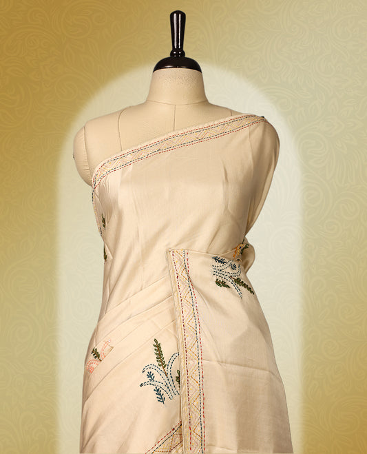 Cream colour pure tussar saree adorned with delicate Peach and green floral embroidery along the border and scattered motifs across the body, paired with a matching blouse.