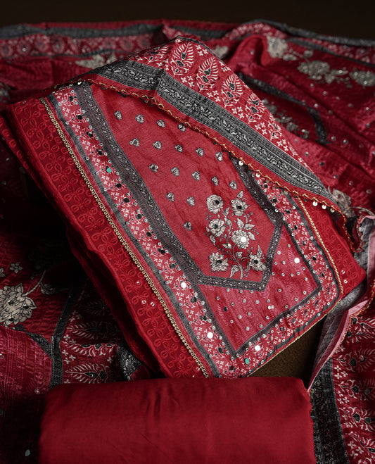 Dark Red colour churidhar material featuring Mirror and thread embroidery, foral print pattern on the self colour front panel, floral digital printed dupatta with elegant border, and matching plain bottom