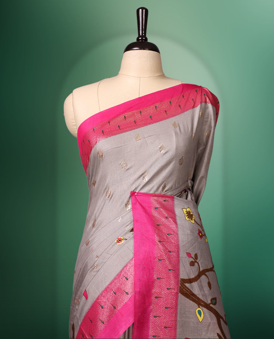 Grey colour saree adorned with delicate woven motifs on the body, enhanced with a vibrant Pink border, complemented by a colourful printed pallu featuring floral and bird designs, and paired with a matching blouse
