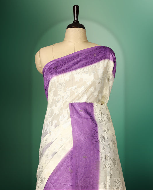 White colour saree adorned with delicate self woven motifs across the body, highlighted with a striking Purple woven border and pallu, finished with tassels, and paired with a matching blouse