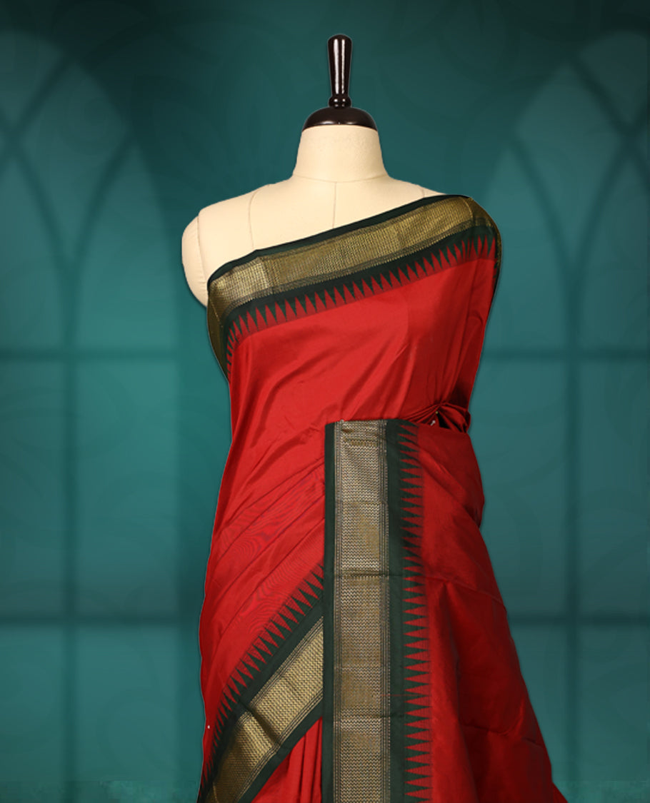 Vibrant Red semi silk saree with plain body, vibrant deep bottle green pallu and matching green border adorned with golden zari, accented with temple motifs along the edges, Paired with a matching blouse, perfect for festive occasions.