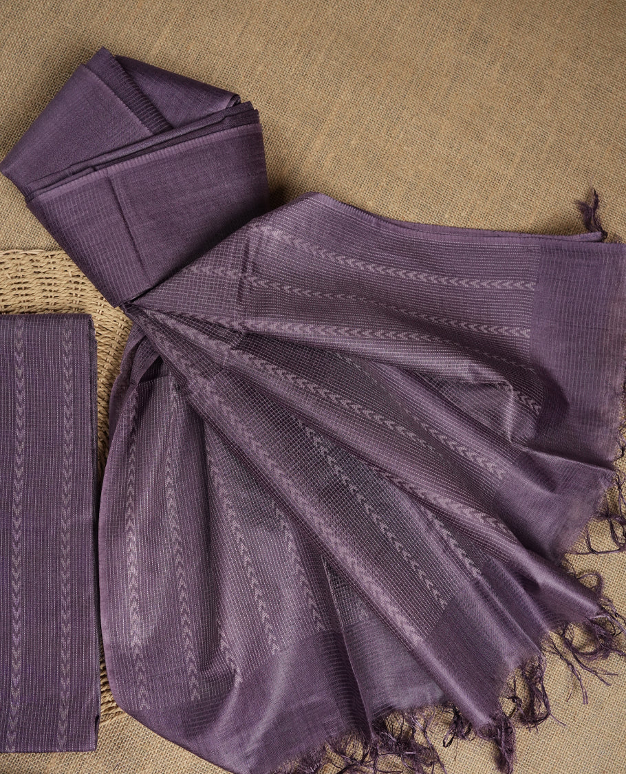 Lavender colour tussar suit material adorned with intricate woven patterns and subtle motifs, exuding ethnic elegance & Paired with a beautifully bordered dupatta and a matching plain bottom.