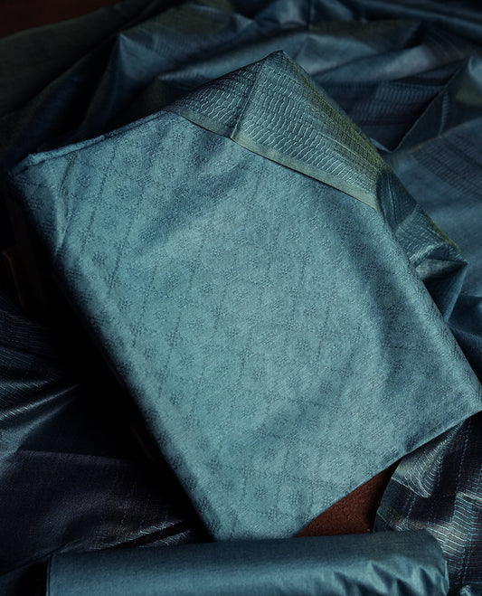 Teal blue colour churidhar material featuring elegant self jacquard design on the body, complemented by a rich woven border & Comes with a matching dupatta with tassels and plain bottom.