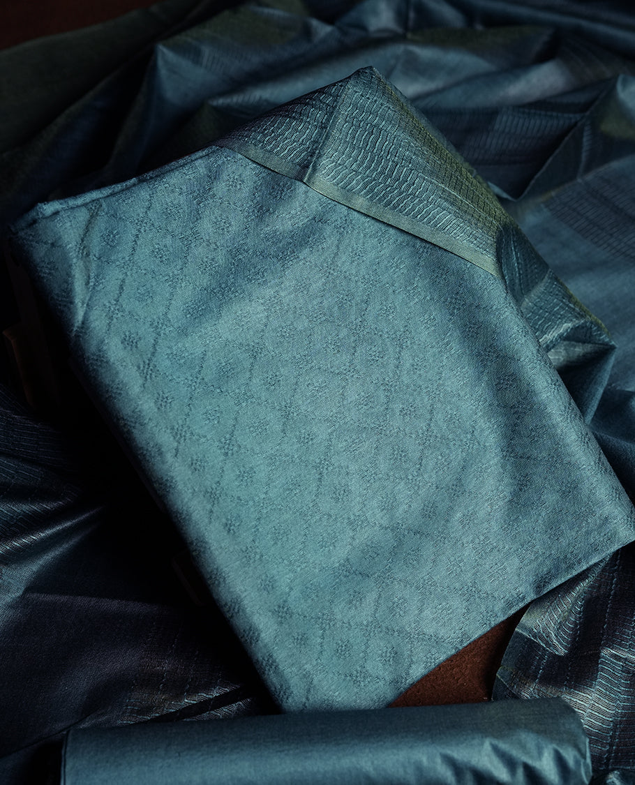 Teal blue colour churidhar material featuring elegant self jacquard design on the body, complemented by a rich woven border & Comes with a matching dupatta with tassels and plain bottom.