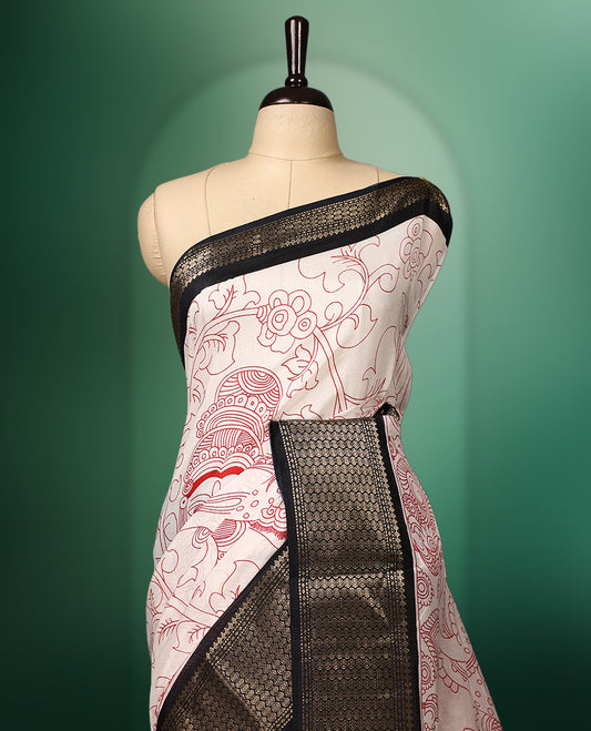 off white colour saree adorned with intricate red Kalamkari style motifs, complemented by a bold red pallu featuring traditional designs, and finished with a rich black woven border, paired with a matching blouse