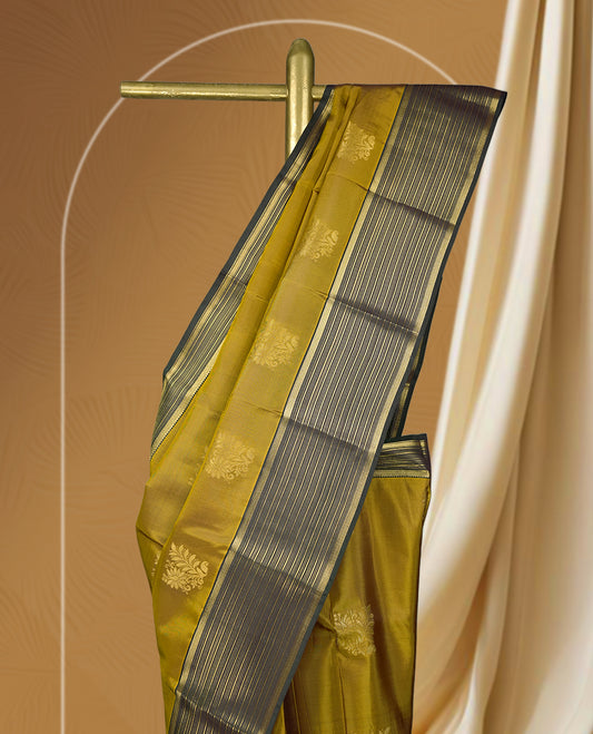 Mustard yellow colour soft silk saree with elegant golden zari motifs, paired with a contrasting dark green border adorned with fine zari stripes & Comes with a matching blouse.