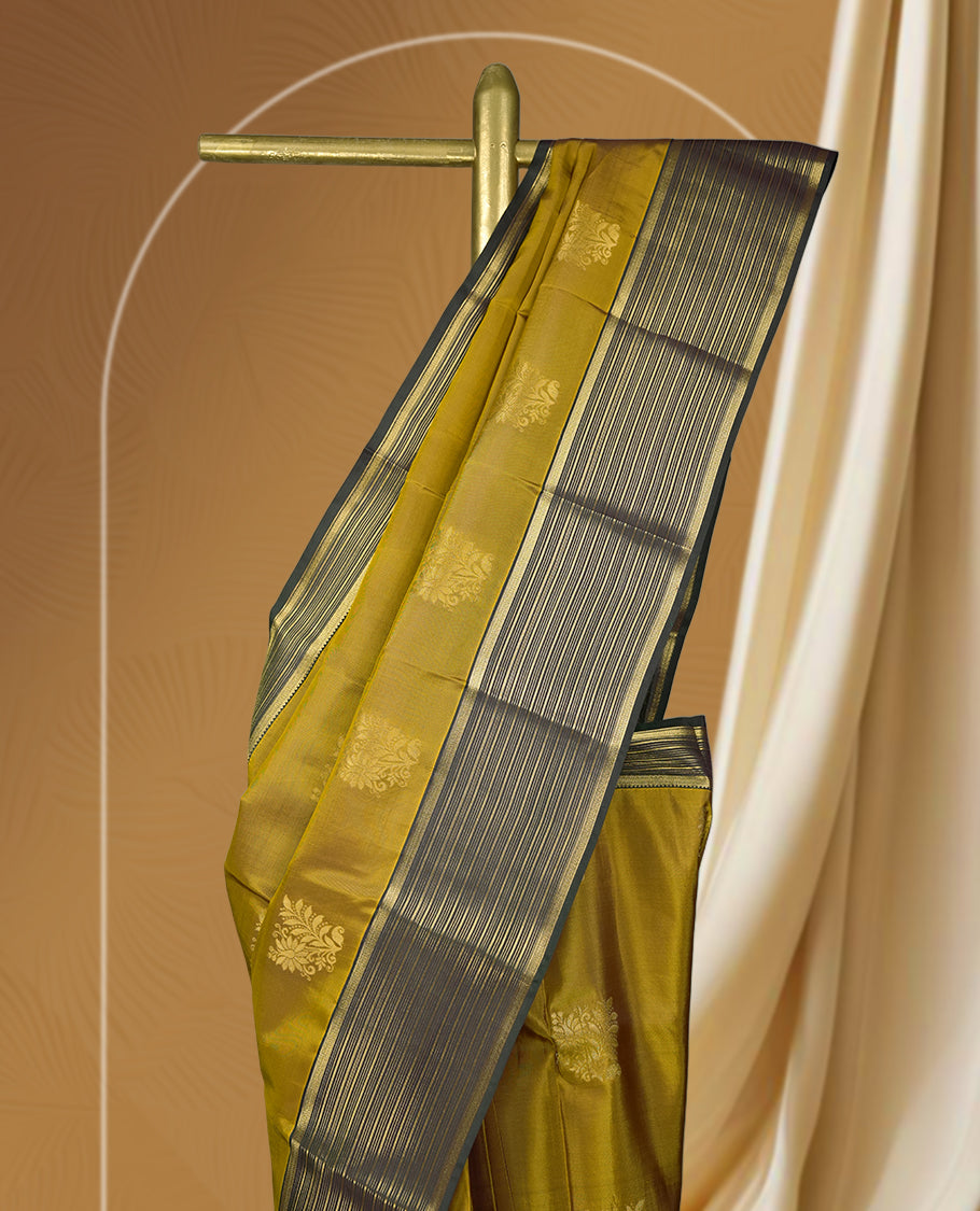 Mustard yellow colour soft silk saree with elegant golden zari motifs, paired with a contrasting dark green border adorned with fine zari stripes & Comes with a matching blouse.