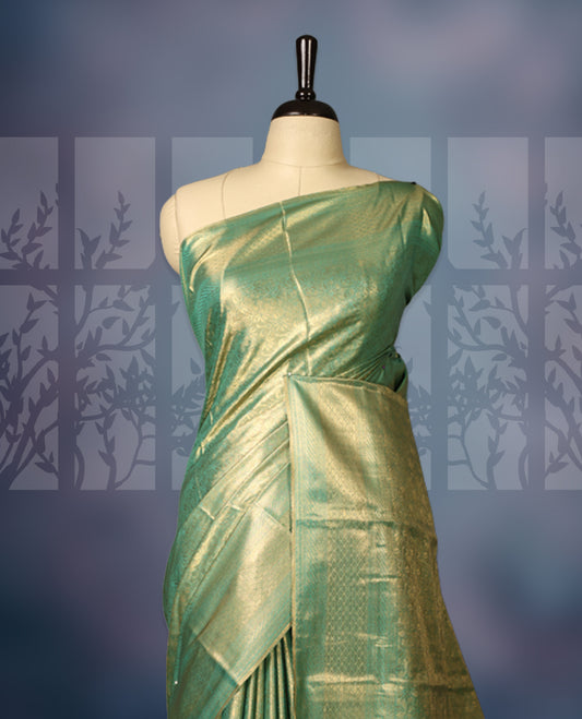 Green semi silk brocade saree featuring delicate self brocade motifs across the body, enhanced with a soft gold toned woven border and pallu, Includes a matching blouse for a graceful ethnic look.