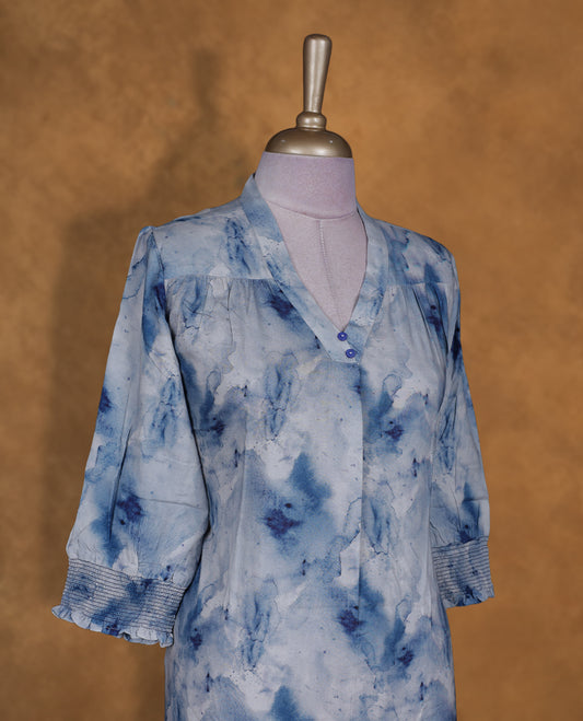 Light blue colour tie dye kurti BY VISMAY with darker blue floral accents, straight calf length silhouette, featuring a V notch neckline and three quarter sleeves with gathered cuffs.