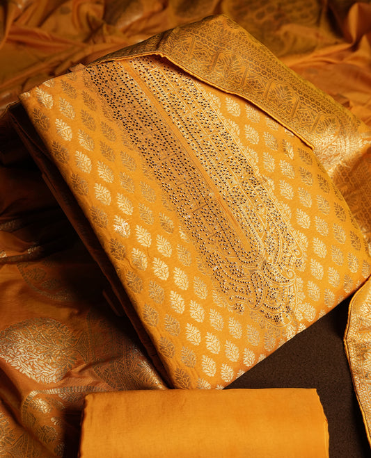 Mustard yellow colour churidar material featuring small golden stone work on the neckline, adorned with zari leaf motifs all over & Comes with a rich zari woven dupatta and matching plain bottom.