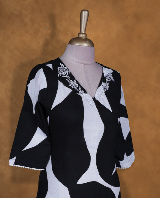 Black and white colour abstract printed kurti by Talisha with V neckline, floral neck embroidery, A‑line knee‑length silhouette, elbow‑length sleeves, and fringe lace at the hem.