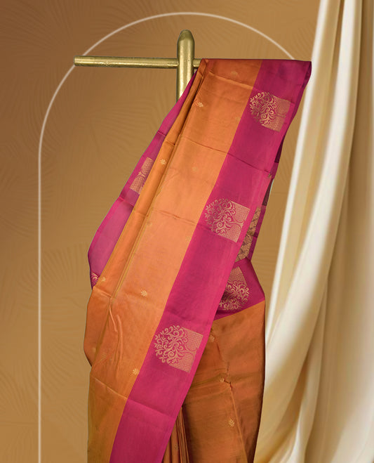 Rich copper brown colour soft silk saree with a contrasting magenta border and pallu, adorned with intricate golden motif & Paired with a matching blouse.