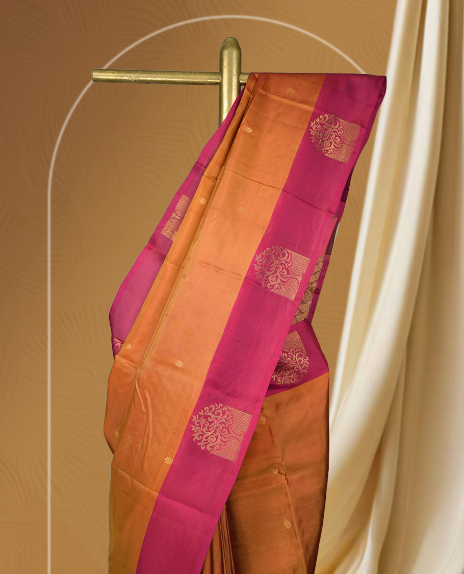 Rich copper brown colour soft silk saree with a contrasting magenta border and pallu, adorned with intricate golden motif & Paired with a matching blouse.