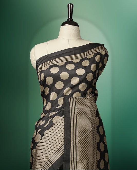 Charcoal Black colour saree featuring bold golden polka dot motifs all over the body, complemented by a sleek striped woven border and pallu, and paired with a matching blouse