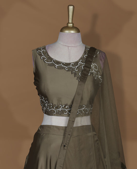 Olive brown colour lehenga set with stitched sleeveless embroidered blouse, matching stitched flared lehenga, and plain sheer dupatta with satin border.