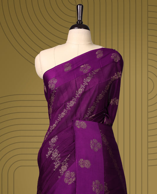 Deep purple semi Banaras tussar saree adorned with golden floral motifs in diagonal patterns across the body and a finely woven zari border, finished with a rich golden pallu, paired with a matching blouse.