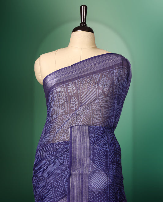 Blue colour saree featuring intricate woven geometric and floral patterns across the body and pallu, highlighted with a subtle striped border and tassels, paired with a matching blouse