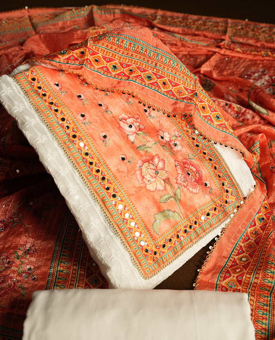 White colour churidhar material featuring Mirror and thread embroidery, foral print pattern on the contrast Orange colour front panel, floral digital printed dupatta with elegant border, and matching plain bottom