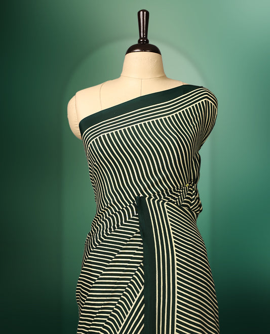 Deep green colour semi modal silk saree featuring elegant cream stripes across the body, complemented by a sleek self colour plain border, and paired with a matching blouse