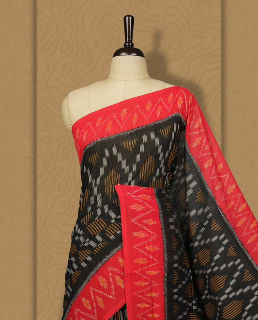 Black colour Ikkat Pochampally saree featuring a vibrant red border and pallu adorned with traditional ikat motifs in shades of beige & grey, bringing a perfect blend of heritage and modern charm.
