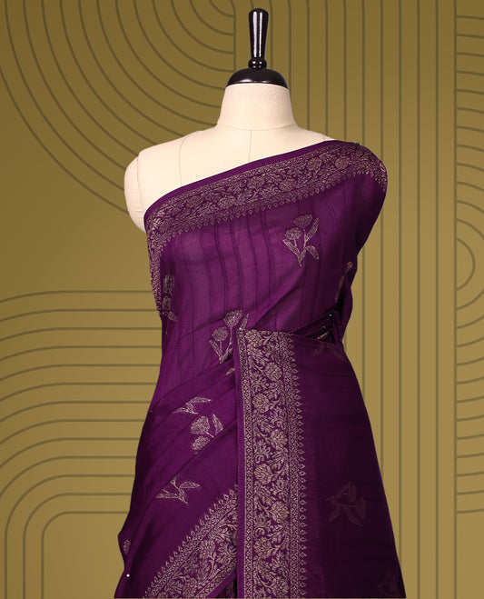 Wine colour semi Banaras tussar saree adorned with golden floral motifs along the border and scattered across the body, finished with a rich golden zari pallu, paired with a matching blouse.